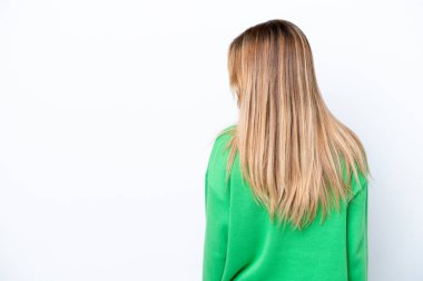 Young Uruguayan woman isolated on white background in back position and looking side