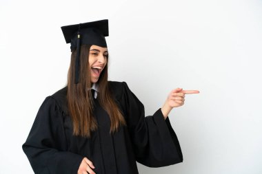 Genç üniversite mezunu, beyaz arka planda izole edilmiş bir şekilde parmak ucunda bir ürün sunuyor.