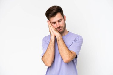 Beyaz arka planda izole edilmiş genç beyaz bir adam uyku jesti yapıyor.