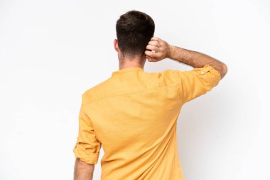 Beyaz arka planda beyaz tenli genç bir adam izole edilmiş ve düşünüyor.