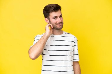 Sarı arka planda izole edilmiş genç beyaz adam gülüyor.