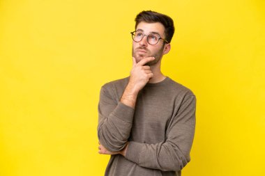 Sarı arka planda izole edilmiş genç beyaz adamın şüpheleri var.