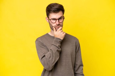 Sarı arka planda izole edilmiş genç beyaz adamın şüpheleri var.