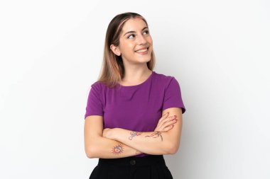 Beyaz arka planda izole edilmiş genç beyaz kadın gülümserken yukarı bakıyor.