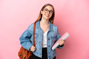Young caucasian student woman isolated on pink background posing with arms at hip and smiling