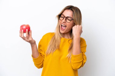 Young Uruguayan woman with an apple isolated on white background celebrating a victory