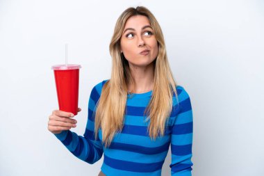 Young Uruguayan woman drinking soda isolated on white background and looking up