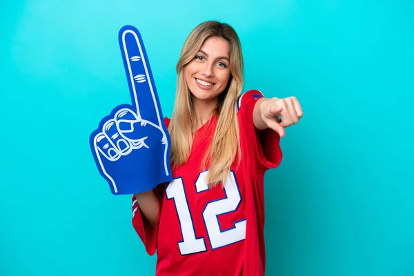 Uruguayan sports fan woman isolated on blue background pointing front with happy expression