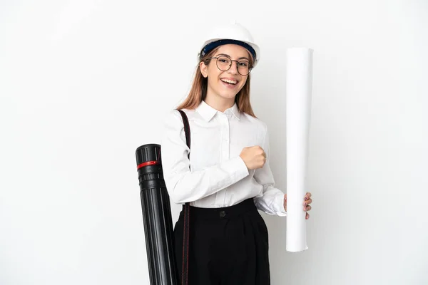 Young architect woman with helmet and holding blueprints isolated on white background celebrating a victory