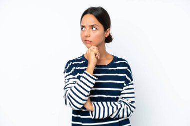 Young hispanic woman isolated on white background having doubts and with confuse face expression