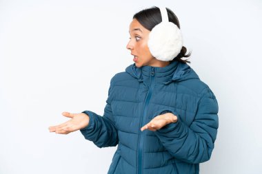 Young hispanic woman wearing a winter earmuffs isolated on white background with surprise facial expression
