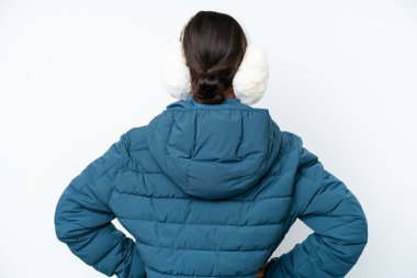 Young hispanic woman wearing a winter earmuffs isolated on white background in back position