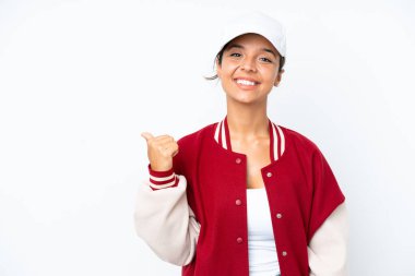 Young hispanic woman wearing a baseball uniform isolated on white background pointing to the side to present a product