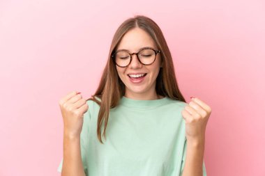 Genç Litvanyalı kadın pembe arka planda gözlüklü ve zaferi kutluyor.
