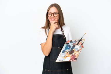 Litvanyalı genç bir kadın beyaz arka planda izole edilmiş bir palet tutuyor. Yan tarafa bakıyor ve gülümsüyor.