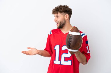 Beyaz arka planda ragbi oynayan beyaz tenli genç bir adam şaşırmış bir ifadeyle yan tarafa bakıyor.