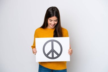 Beyaz arka planda izole edilmiş genç Brezilyalı bir kadın barış sembollü bir pankart tutuyor.
