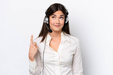 Beyaz arka planda izole edilmiş bir kulaklıkla çalışan beyaz pazarlamacı kadın işaret parmağıyla işaret etmek harika bir fikir.