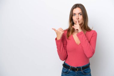 Beyaz arka planda izole edilmiş genç beyaz bir kadın yan tarafı işaret ediyor ve sessiz hareketler yapıyor.