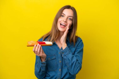 Sarı arka planda saşimi tutan beyaz bir kadın ağzı açık bağırıyor.