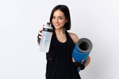 Beyaz arka planda izole edilmiş beyaz tenli genç bir kadın spor su şişesi ve bir paspas ile