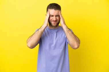 Sarışın yakışıklı, soyutlanmış, sarı arka planlı, baş ağrısı olan bir adam.