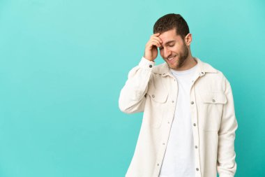 Yakışıklı sarışın adam, soyutlanmış mavi arka planda gülüyor.