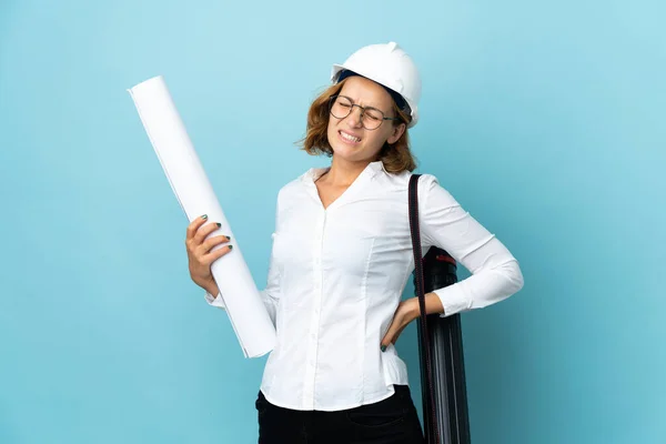 Young architect Georgian woman with helmet and holding blueprints over isolated background suffering from backache for having made an effort