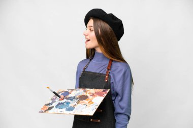 Young artist man holding a palette over isolated white background laughing in lateral position