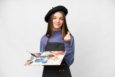 Young artist man holding a palette over isolated white background making money gesture