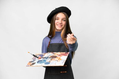 Young artist man holding a palette over isolated white background making money gesture