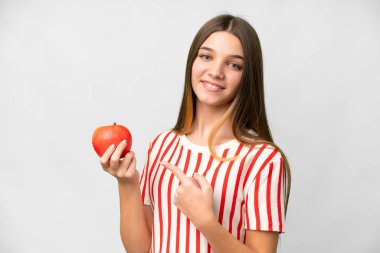 Teenager girl with an apple over isolated white background and pointing it