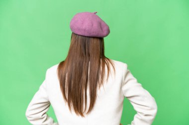 Young beautiful woman over isolated chroma key background in back position