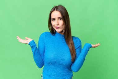 Young beautiful woman over isolated chroma key background having doubts while raising hands