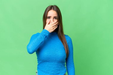 Young beautiful woman over isolated chroma key background covering mouth with hand