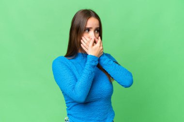 Young beautiful woman over isolated chroma key background covering mouth and looking to the side