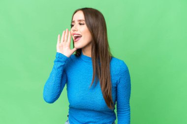 Young beautiful woman over isolated chroma key background shouting with mouth wide open to the side