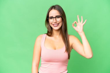 Young beautiful woman over isolated chroma key background With glasses and doing OK sign