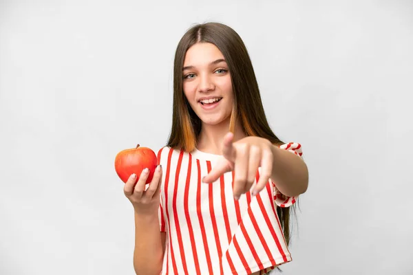 Teenager girl with an apple over isolated white background points finger at you with a confident expression