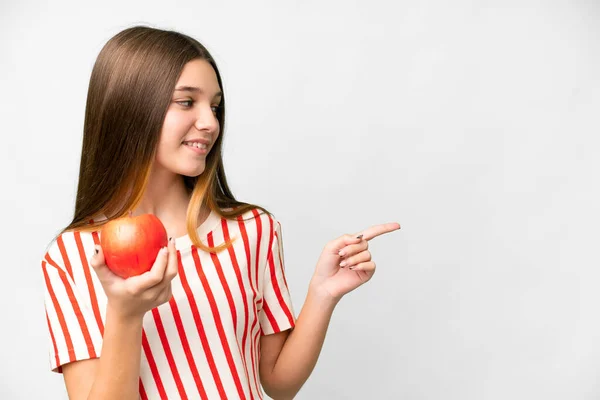 Teenager girl with an apple over isolated white background pointing to the side to present a product