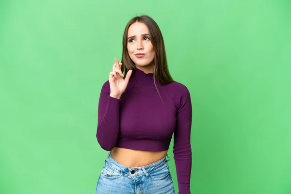 Young beautiful woman over isolated chroma key background with fingers crossing and wishing the best