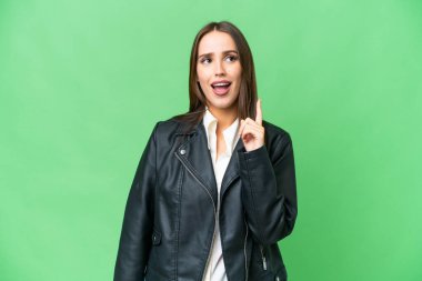 Young beautiful woman over isolated chroma key background thinking an idea pointing the finger up