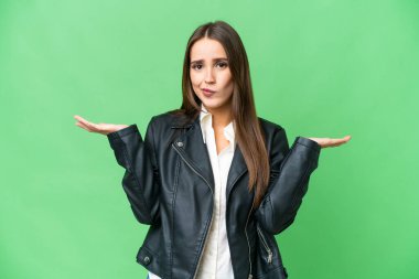 Young beautiful woman over isolated chroma key background having doubts while raising hands