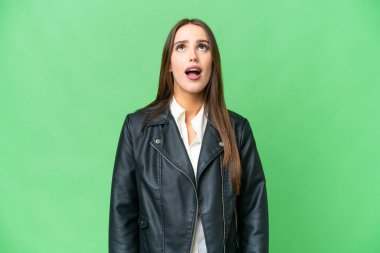 Young beautiful woman over isolated chroma key background looking up and with surprised expression