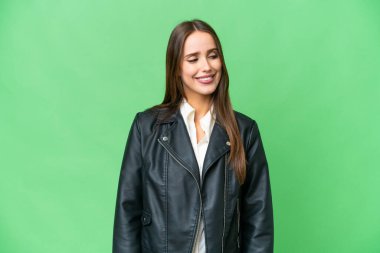 Young beautiful woman over isolated chroma key background looking to the side and smiling
