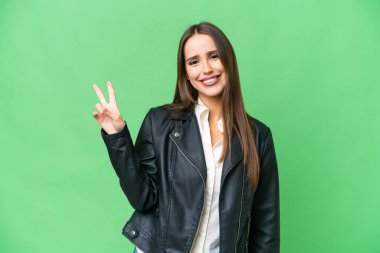 Young beautiful woman over isolated chroma key background smiling and showing victory sign