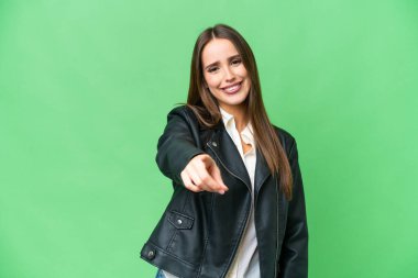 Young beautiful woman over isolated chroma key background pointing front with happy expression