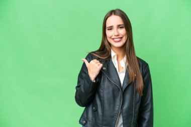 Young beautiful woman over isolated chroma key background pointing to the side to present a product