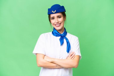 Airplane stewardess over isolated chroma key background keeping the arms crossed in frontal position