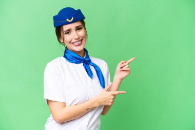 İzole edilmiş kroma anahtar arka plan üzerinde uçak hostesi parmak göstererek bir ürün sunar